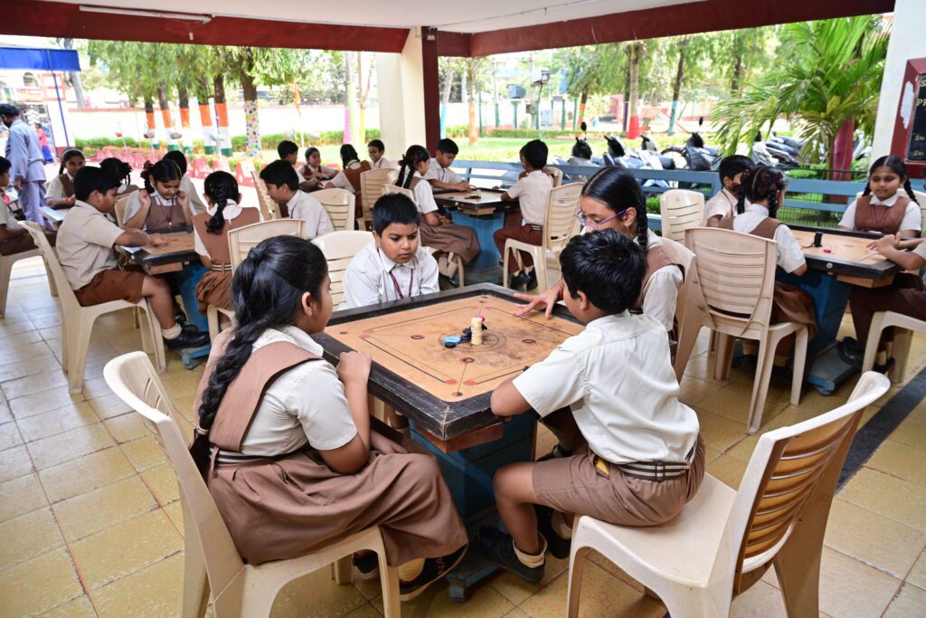 Student playing carrom in the indoor games area at Sir C.R. Reddy School